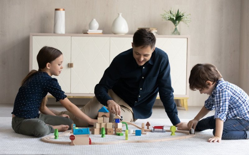 /assets/img/51788571-dad-and-kids-play-toy-railroad-at-home.jpg