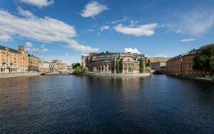 Västra riksdagshuset speglas i Strömmen. Till vänster i bild syns Rosenbad. Foto: Melker Dahlstrand / Sveriges riksdag