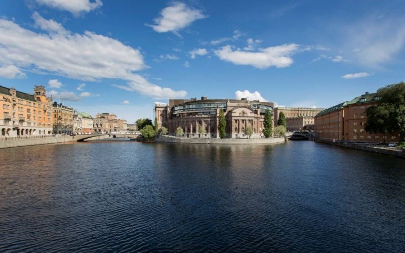 Västra riksdagshuset speglas i Strömmen. Till vänster i bild syns Rosenbad. Foto: Melker Dahlstrand / Sveriges riksdag