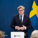 Justitieminister Gunnar Strömmer håller presskonferens vid talarpodium med svenska flaggan i bakgrunden